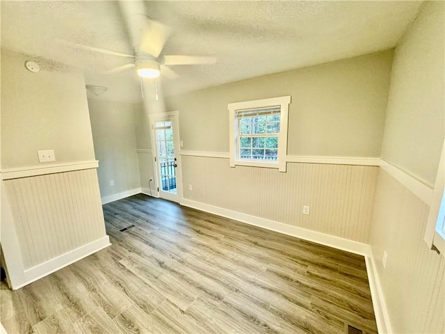 spare room featuring hardwood / wood-style flooring, ceiling fan, and a textured ceiling