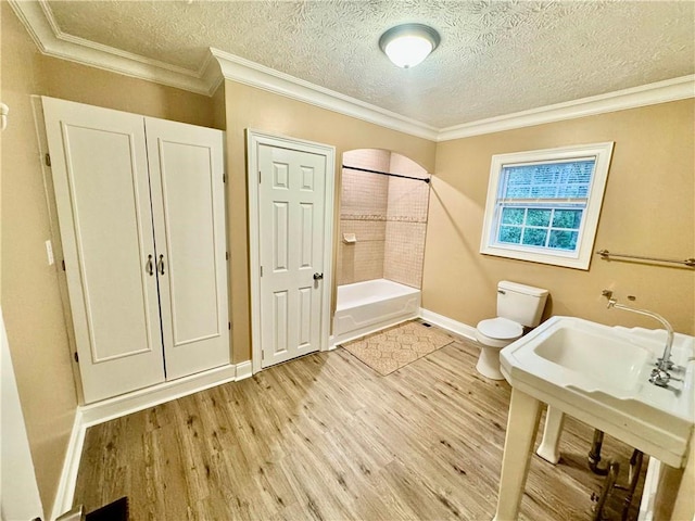 bathroom with bathing tub / shower combination, ornamental molding, a textured ceiling, hardwood / wood-style floors, and toilet