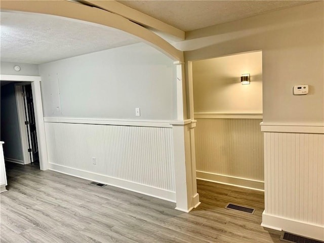 empty room with wood walls, hardwood / wood-style floors, and a textured ceiling