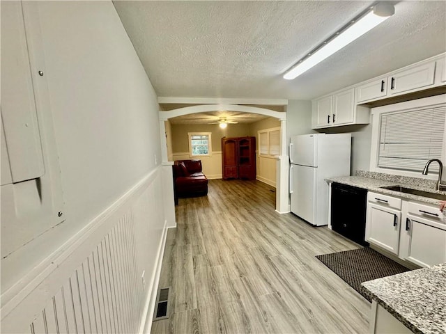 kitchen with black dishwasher, sink, white fridge, white cabinetry, and light hardwood / wood-style flooring