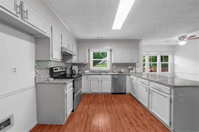 1410 Kingfield Dr, Johns Creek, GA 30005 - kitchen with appliances with stainless steel finishes, a peninsula, under cabinet range hood, tasteful backsplash, and light stone counters