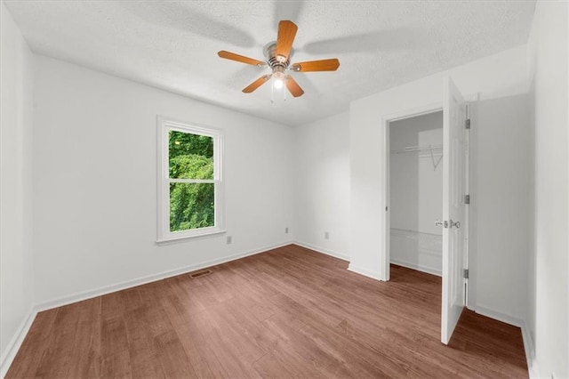 1410 Kingfield Dr, Johns Creek, GA 30005 - unfurnished bedroom featuring wood finished floors, a closet, a walk in closet, a textured ceiling, and ceiling fan