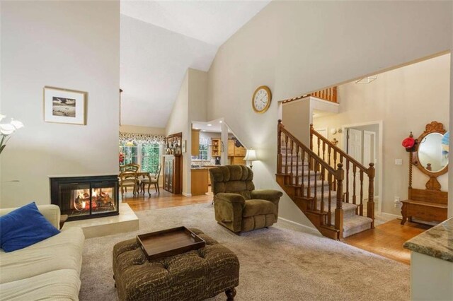 living area featuring a multi sided fireplace, vaulted ceiling, and light colored carpet