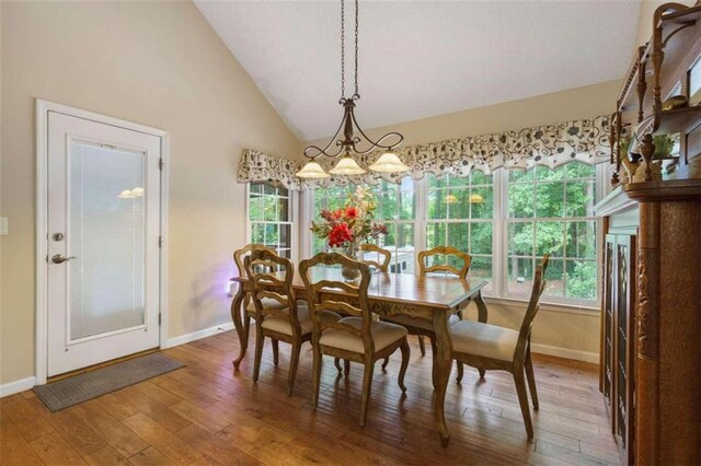 dining area with lofted ceiling, wood-type flooring, and a chandelier