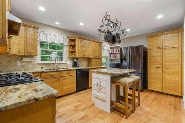 kitchen with white cabinetry, stainless steel appliances, light stone countertops, light hardwood / wood-style floors, and backsplash