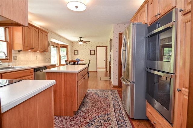 4366 Cedar Wood Dr SW, Lilburn, GA 30047 - kitchen featuring appliances with stainless steel finishes, a kitchen island, light countertops, wood finished floors, and wallpapered walls