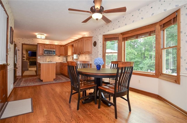 4366 Cedar Wood Dr SW, Lilburn, GA 30047 - dining room with wallpapered walls, light wood finished floors, baseboards, and a ceiling fan