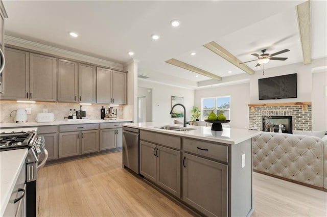 kitchen with appliances with stainless steel finishes, beam ceiling, light countertops, and a sink