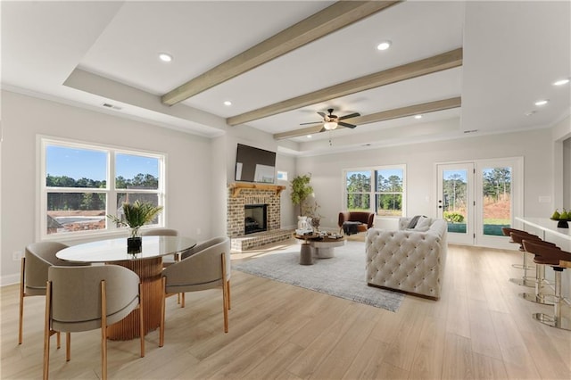 living room featuring visible vents, light wood-style flooring, beamed ceiling, a fireplace, and recessed lighting