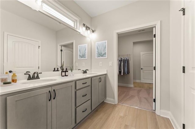 bathroom with double vanity, baseboards, a sink, and wood finished floors