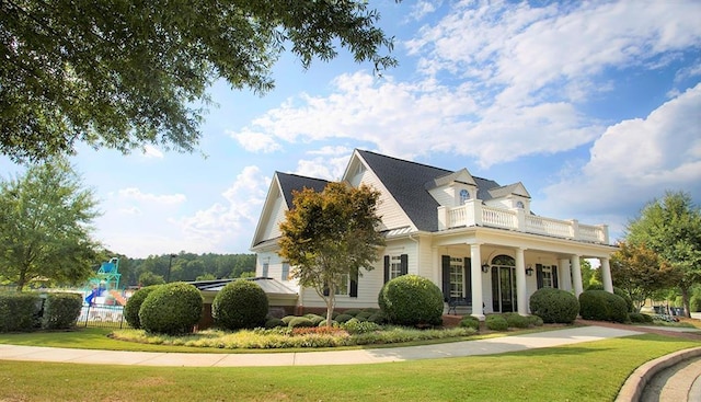 view of front of property featuring a balcony and a front lawn