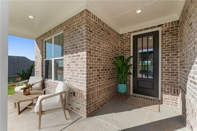 view of exterior entry featuring covered porch and brick siding