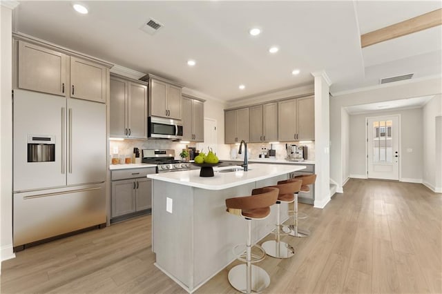 kitchen with appliances with stainless steel finishes, a sink, gray cabinetry, and ornamental molding