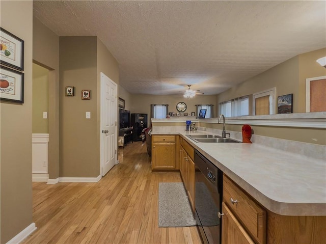 kitchen featuring a textured ceiling, a sink, light wood-style floors, black dishwasher, and light countertops