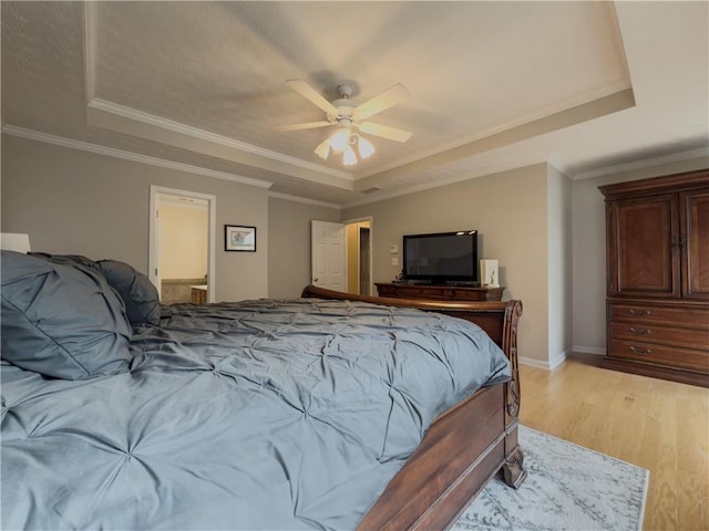 bedroom featuring crown molding, a tray ceiling, and light wood-style floors