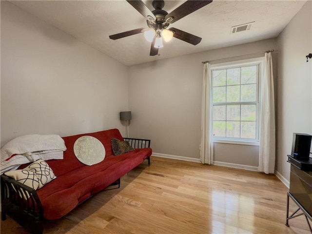 living area with a ceiling fan, visible vents, light wood-style flooring, and baseboards