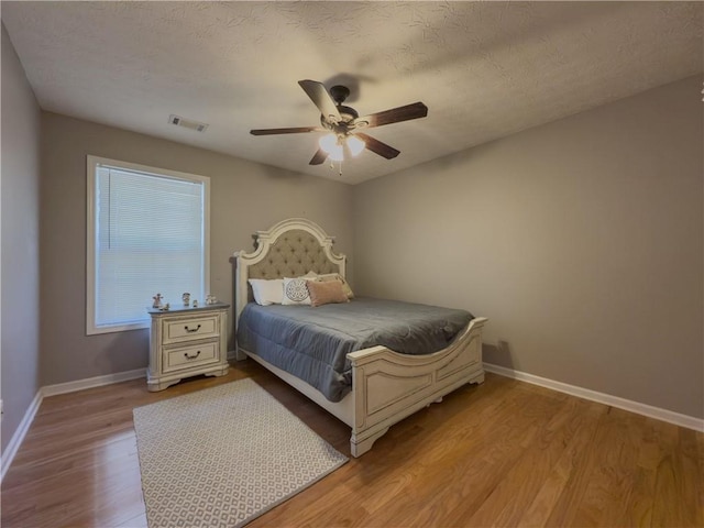 bedroom featuring baseboards, visible vents, ceiling fan, and wood finished floors