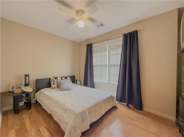 bedroom featuring light wood-style flooring, visible vents, baseboards, and a ceiling fan