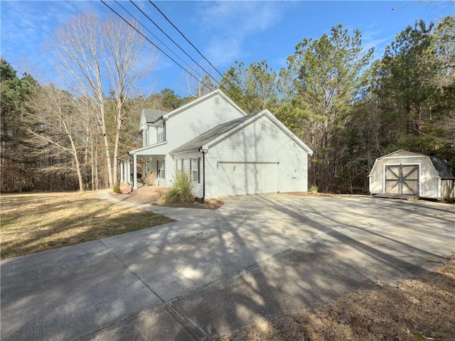 view of side of home with a garage, concrete driveway, an outbuilding, a shed, and a porch