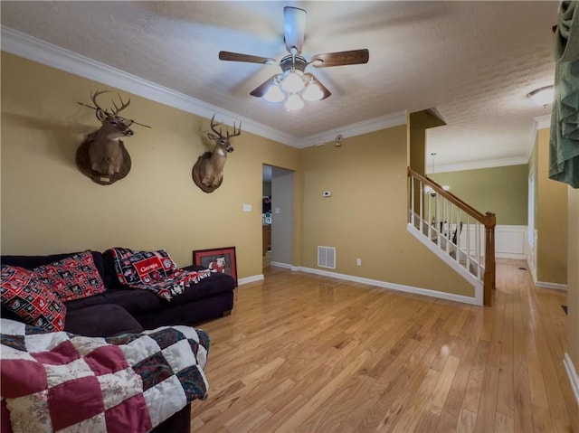 living area featuring visible vents, stairway, ornamental molding, light wood-type flooring, and baseboards