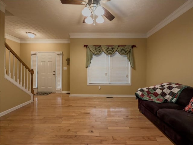 living area featuring light wood-type flooring, stairway, and ornamental molding