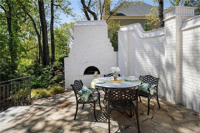 view of patio featuring an outdoor brick fireplace and outdoor dining area