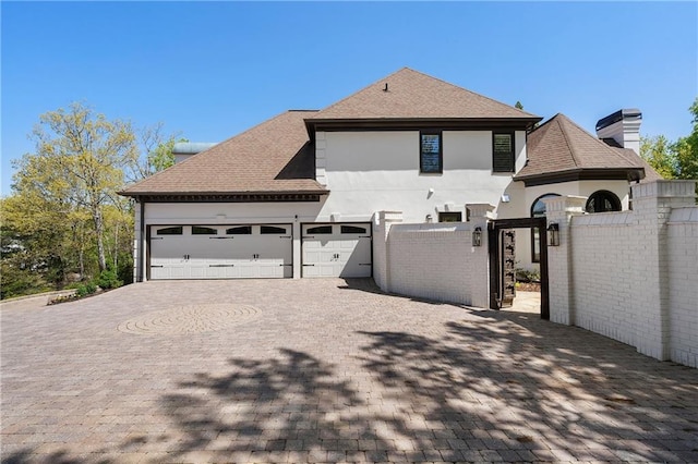 view of front of property featuring a gate, a shingled roof, decorative driveway, and an attached garage