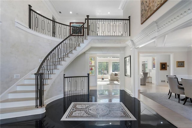 interior space with a towering ceiling, crown molding, recessed lighting, and baseboards