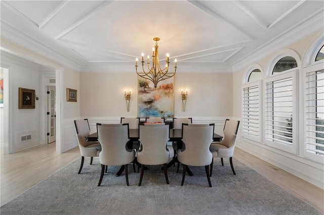 dining area featuring visible vents, ornamental molding, a notable chandelier, and light wood-style floors