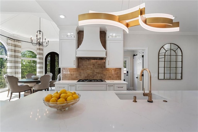 kitchen featuring gas cooktop, ornamental molding, premium range hood, and a sink