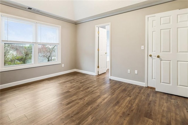 unfurnished bedroom with visible vents, baseboards, and dark wood-style flooring