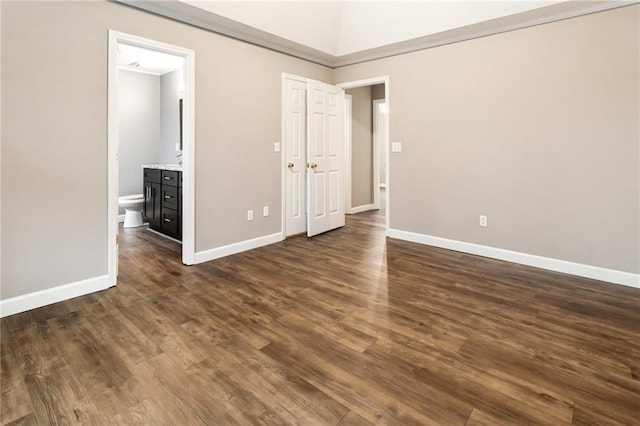 unfurnished bedroom featuring connected bathroom, baseboards, and dark wood-style flooring