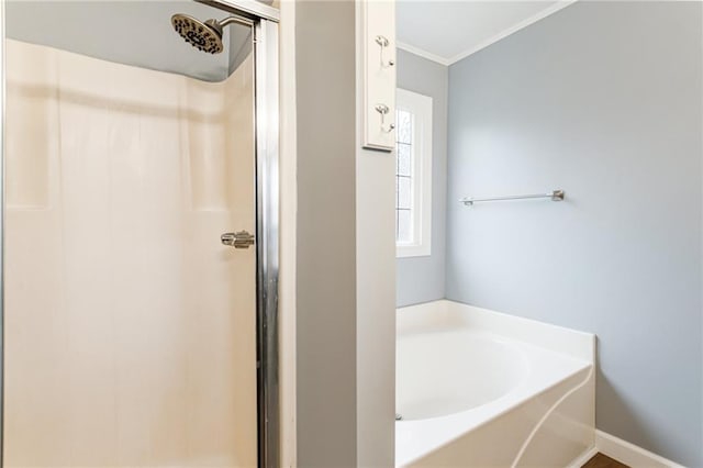 full bath with a stall shower, baseboards, a garden tub, and ornamental molding