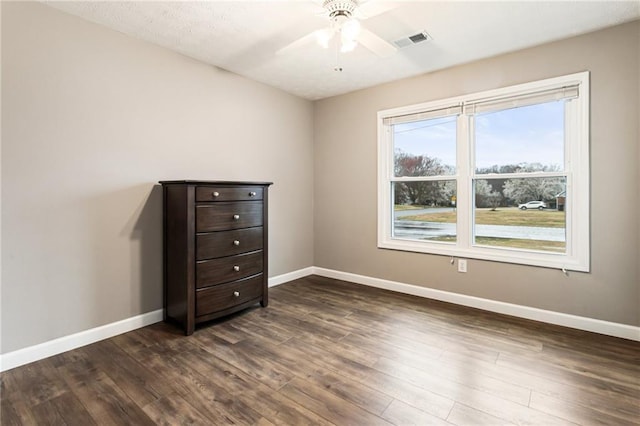 unfurnished room with visible vents, baseboards, a ceiling fan, and dark wood-style flooring