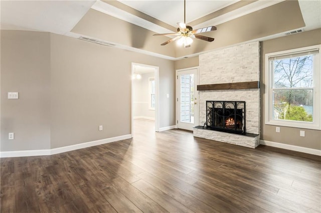 unfurnished living room with dark wood-style floors, visible vents, a stone fireplace, and a raised ceiling