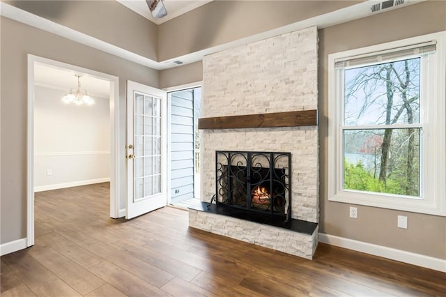 unfurnished living room with visible vents, baseboards, wood finished floors, and a fireplace