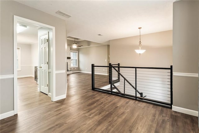 hall featuring baseboards, an upstairs landing, visible vents, and wood finished floors