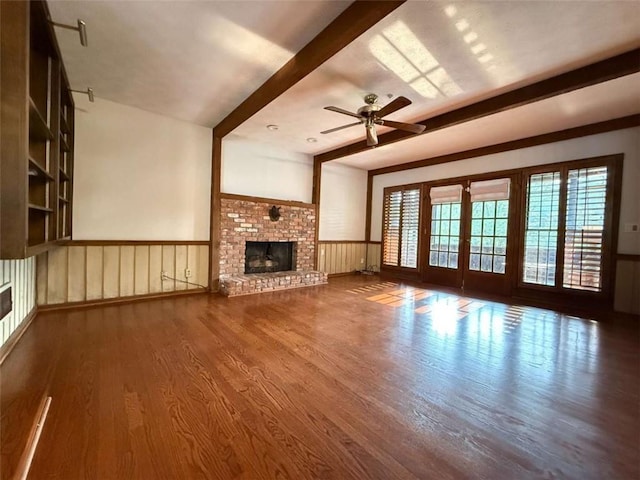 8710 Mount Rushmore Dr, Johns Creek, GA 30022 - unfurnished living room featuring wood finished floors, beamed ceiling, wainscoting, a ceiling fan, and a fireplace