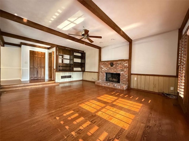 8710 Mount Rushmore Dr, Johns Creek, GA 30022 - unfurnished living room featuring beam ceiling, wood finished floors, ceiling fan, a fireplace, and wainscoting