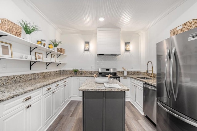 kitchen with a center island, sink, light stone countertops, white cabinetry, and stainless steel appliances