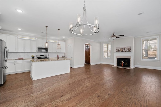 kitchen featuring pendant lighting, appliances with stainless steel finishes, ornamental molding, and a kitchen island with sink