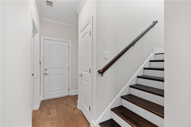 stairway featuring ornamental molding and hardwood / wood-style flooring