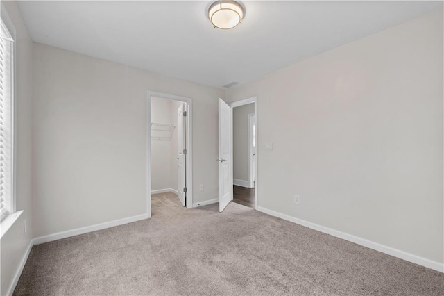 unfurnished bedroom with light colored carpet, a closet, and a walk in closet