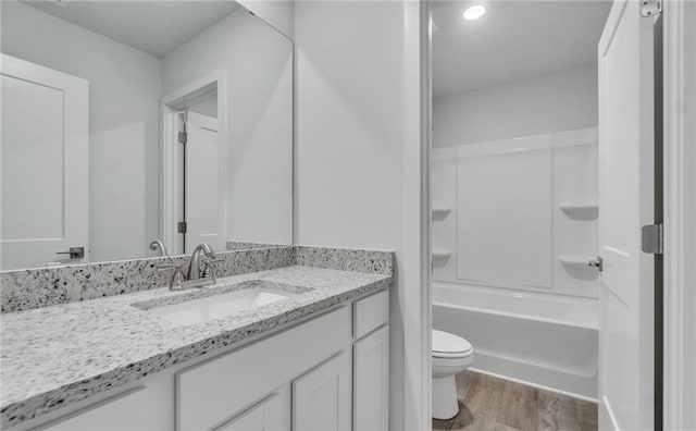 full bathroom with hardwood / wood-style flooring, washtub / shower combination, vanity, and toilet