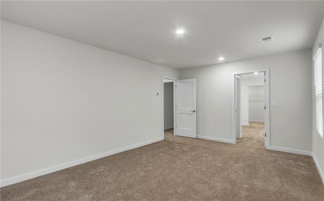 unfurnished bedroom with a spacious closet, light colored carpet, and a closet