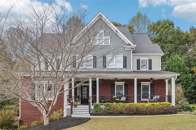 view of front of home featuring a porch, brick siding, a front lawn, and roof with shingles