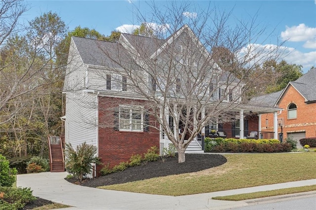 view of front of property featuring a front yard, stairway, and brick siding