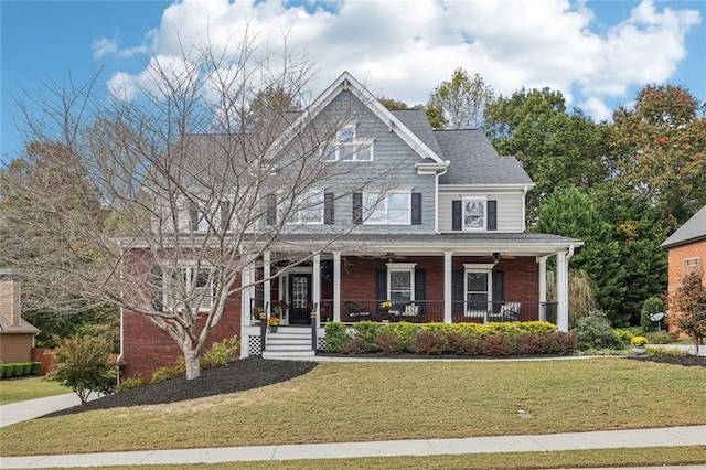 view of front of home with roof with shingles, a front lawn, a porch, and brick siding