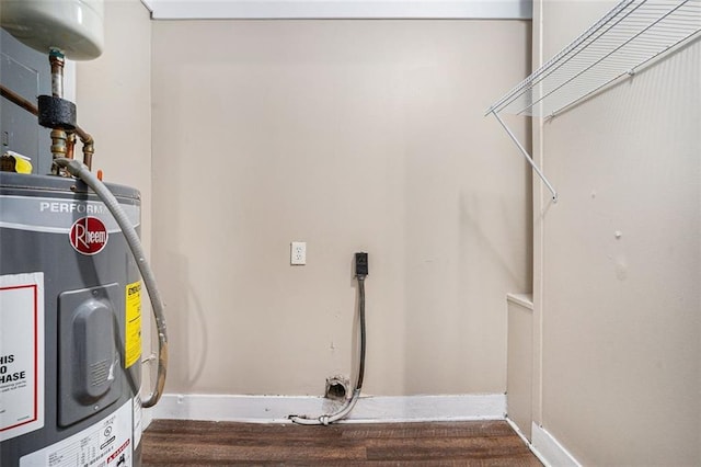 washroom featuring laundry area, baseboards, water heater, and wood finished floors