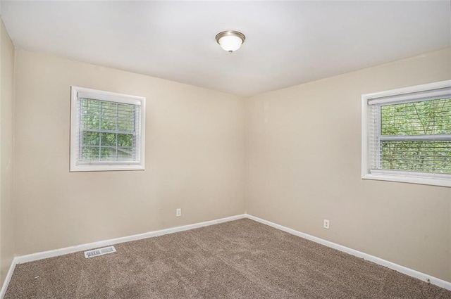 unfurnished room with visible vents, carpet, and baseboards